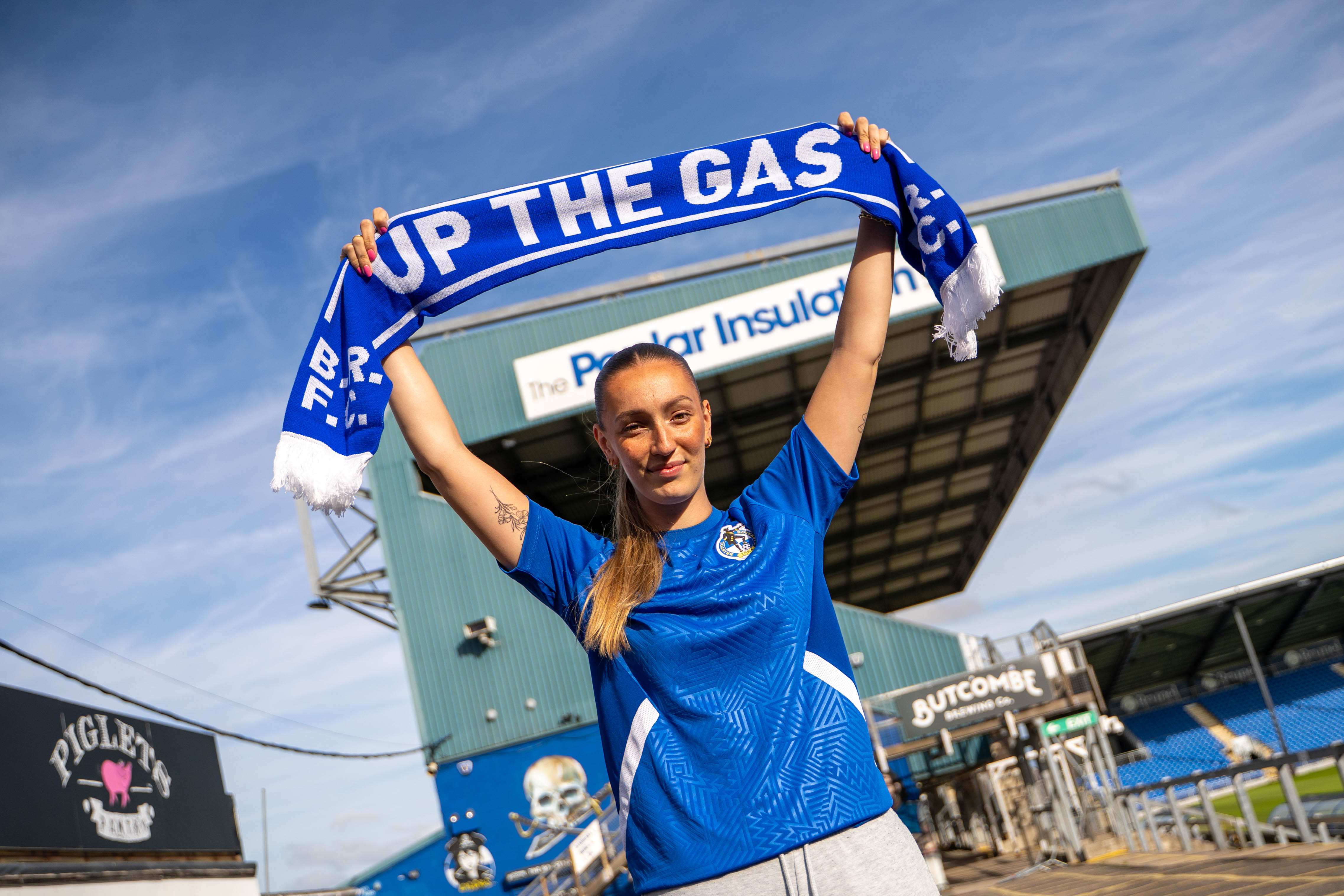 Chloe Gilroy in a Bristol Rovers shirt holding up a Bristol Rovers Scarf.