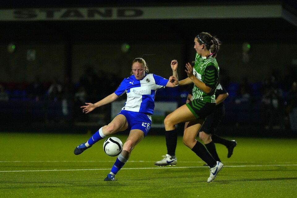 Ellie Preece strikes the ball while being pressured by a defender.